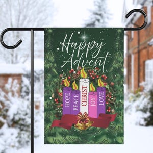 May include: A garden flag with a green background and the words "Happy Advent" in white script. The flag features a wreath of pine needles, berries, and four candles in purple, white, and pink, with the words "Hope, Peace, Christ, Joy, Love". A red ribbon and gold bells are at the bottom.