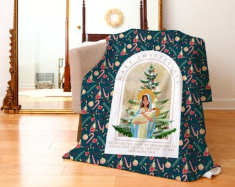 Pode incluir: Uma manta de microfibra azul turquesa com uma borda branca que apresenta uma cena de Natal com Maria e o menino Jesus. A manta tem um padrão repetido de bengalas de doces, enfeites e velas. O texto "Mary Invites All" está escrito em um arco dourado sobre a cena. O texto abaixo da cena diz "To enter the cave of Bethlehem, to adore and to kiss the feet of her new-born son."