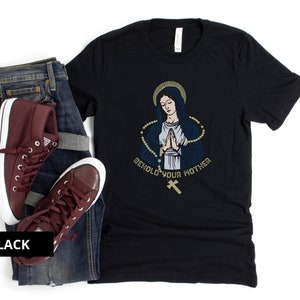 May include: Black t-shirt with a graphic of a woman in a blue robe with a gold rosary and the text "Behold Your Mother".