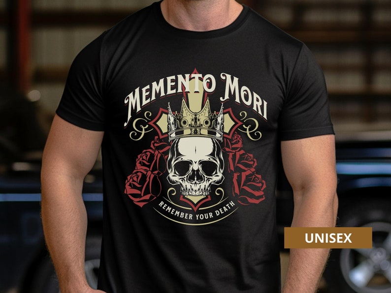 Pode incluir: Camiseta preta com uma caveira usando uma coroa e cercada por rosas. O texto "Memento Mori" est&aacute; acima da caveira e "Remember Your Death" est&aacute; abaixo. A palavra "UNISEX" est&aacute; no canto inferior direito.