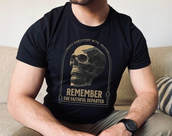 Puede incluir: Una camiseta negra con un gráfico de calavera y el texto "Empty Purgatory with Prayers Remember The Faithful Departed".