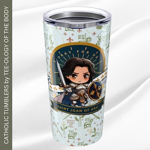 May include: A white stainless steel tumbler with a blue and gold design featuring a cartoon image of Saint Joan of Arc holding a sword and shield. The text "Pray for us" is written in a circle around the image. The tumbler is decorated with a repeating pattern of fleurs-de-lis and other symbols.