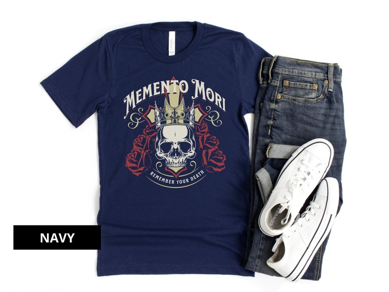 Pode incluir: Uma camiseta azul marinho com um gr&aacute;fico de caveira e coroa e o texto "Memento Mori Remember Your Death".