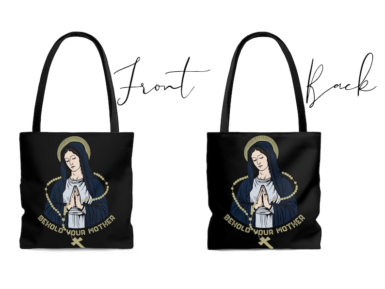 Op de afbeelding: Zwarte tote bag met een afbeelding van de Maagd Maria die bidt met een rozenkrans. De tekst "Behold Your Mother" is onder de afbeelding gedrukt.