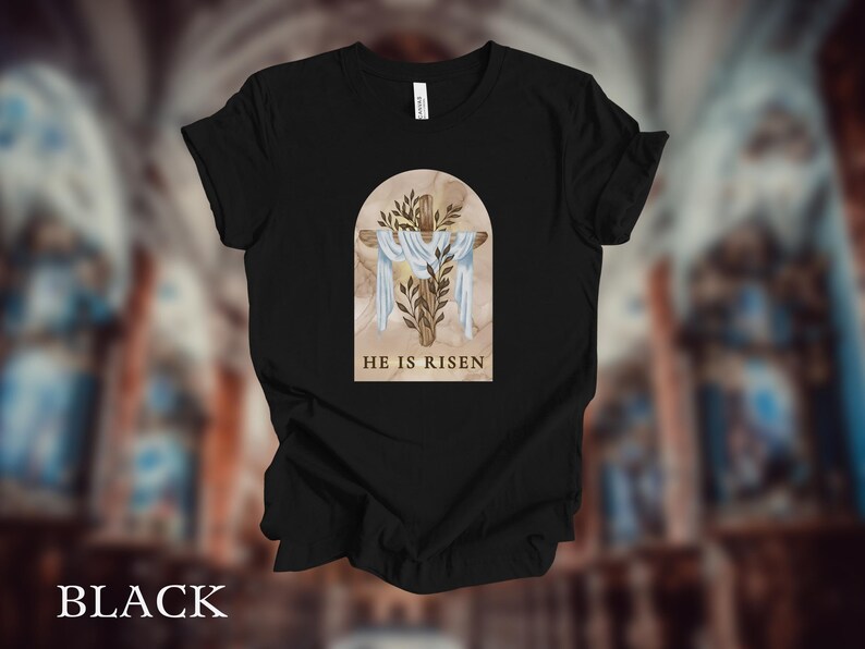 May include: Black t-shirt with a graphic of a cross with a white cloth and green leaves in a brown arch. The text "HE IS RISEN" is below the graphic.