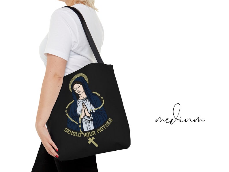 Op de afbeelding: Zwarte tote bag met een afbeelding van de Maagd Maria met een rozenkrans en de tekst "Behold Your Mother".