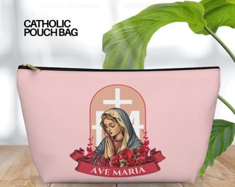May include: A pink Catholic pouch bag with a gold zipper. The bag features an illustration of the Virgin Mary with a cross and the words "AVE MARIA" on a red banner. The text "CATHOLIC POUCH BAG" is printed on the top left.