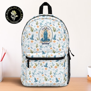 May include: White backpack with a repeating pattern of anchors, seashells, and starfish in blue and orange. The backpack features a central oval design with an image of Our Lady and the text "Our Lady, Stella Maris". A black zipper pocket and side mesh pocket are visible.