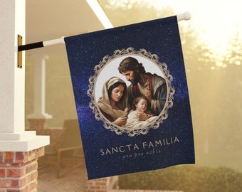May include: A blue and gold religious flag with a picture of the Holy Family, Mary, Joseph, and baby Jesus. The text on the flag reads "Sancta Familia ora pro nobis".
