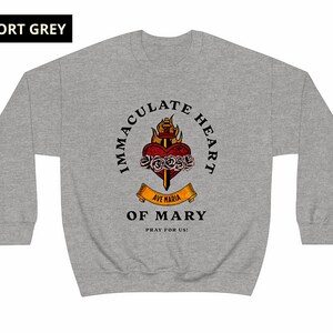 May include: A gray sweatshirt with a graphic of the Immaculate Heart of Mary. The graphic features a heart with a sword, flames, and roses. The text reads "Immaculate Heart of Mary" and "Ave Maria" with a banner that says "Pray for Us!"