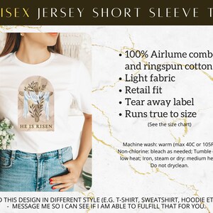 May include: White short-sleeved t-shirt with a blue and brown watercolor design of a cross with the text "He is Risen". The t-shirt is made of 100% Airlume combed and ringspun cotton.