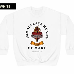 May include: White sweatshirt with a graphic of the Immaculate Heart of Mary. The graphic features a heart with a sword, roses, and flames. The text "Immaculate Heart of Mary" is written in a circle around the graphic. The text "Ave Maria" is written on a banner below the heart. The text "Pray for Us!" is written below the banner.