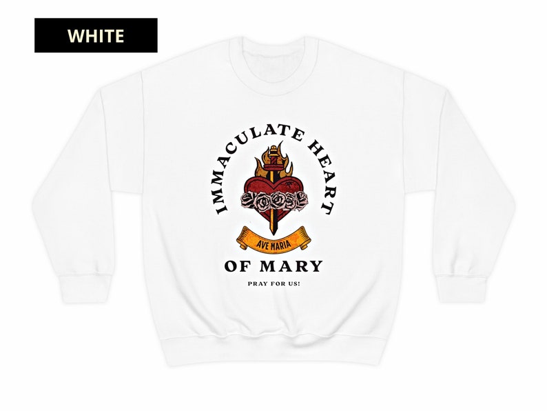 May include: White sweatshirt with a graphic of the Immaculate Heart of Mary. The graphic features a heart with a sword, roses, and flames. The text "Immaculate Heart of Mary" is written in a circle around the graphic. The text "Ave Maria" is written on a banner below the heart. The text "Pray for Us!" is written below the banner.