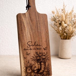 Könnte beinhalten: Rustikales Holzschild mit dem Text "Welcome to our home" in handschriftlichem Stil. Das Schild hat eine Used-Optik und ein schlichtes, einladendes Design, ideal für die Eingangsbereichsdekoration.