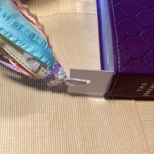 May include: A purple leather-bound book with a silver bookmark attached. The book has a decorative pattern and the text "THE JEREMIAH" is visible on the spine.