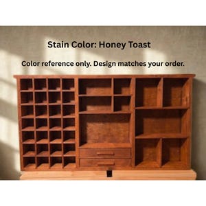 Puede incluir: Un organizador de pared de madera con acabado en tinte honey toast. La unidad cuenta con una rejilla de peque&ntilde;os compartimentos cuadrados a la izquierda, estantes abiertos m&aacute;s grandes en el centro y la derecha, y dos cajones. Texto: Stain Color: Honey Toast.