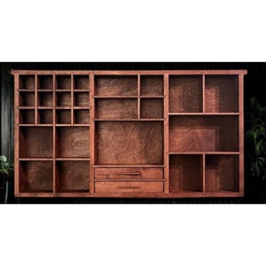 May include: A large, wooden wall-mounted organizer with multiple compartments and two drawers. The organizer is stained a warm brown color, showcasing the wood grain. Various sized shelves and cubbies provide storage options.
