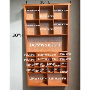 May include: A light brown wooden wall shelf with multiple compartments and drawers. The unit measures 16 inches wide by 30 inches high. It features various cubby sizes including 4.75 by 4.75 inches, 3 by 1.5 inches, 2.25 by 2 inches, and 7.25 by 4.5 inches.