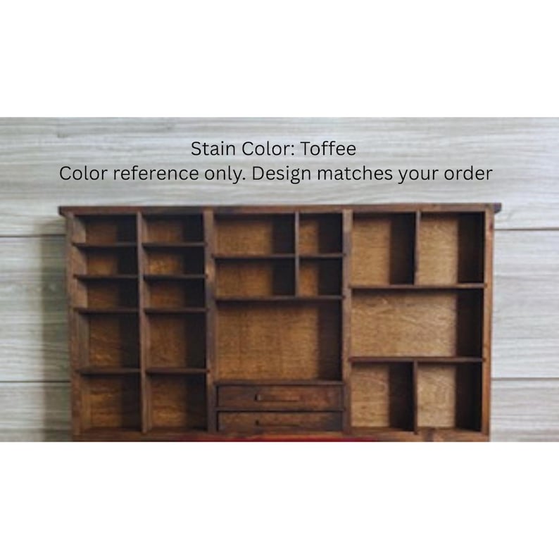 May include: A rectangular wooden display shelf with a toffee-colored stain, featuring multiple compartments of varying sizes and two small drawers at the bottom center. The text above the shelf reads: Stain Color: Toffee. Color reference only.