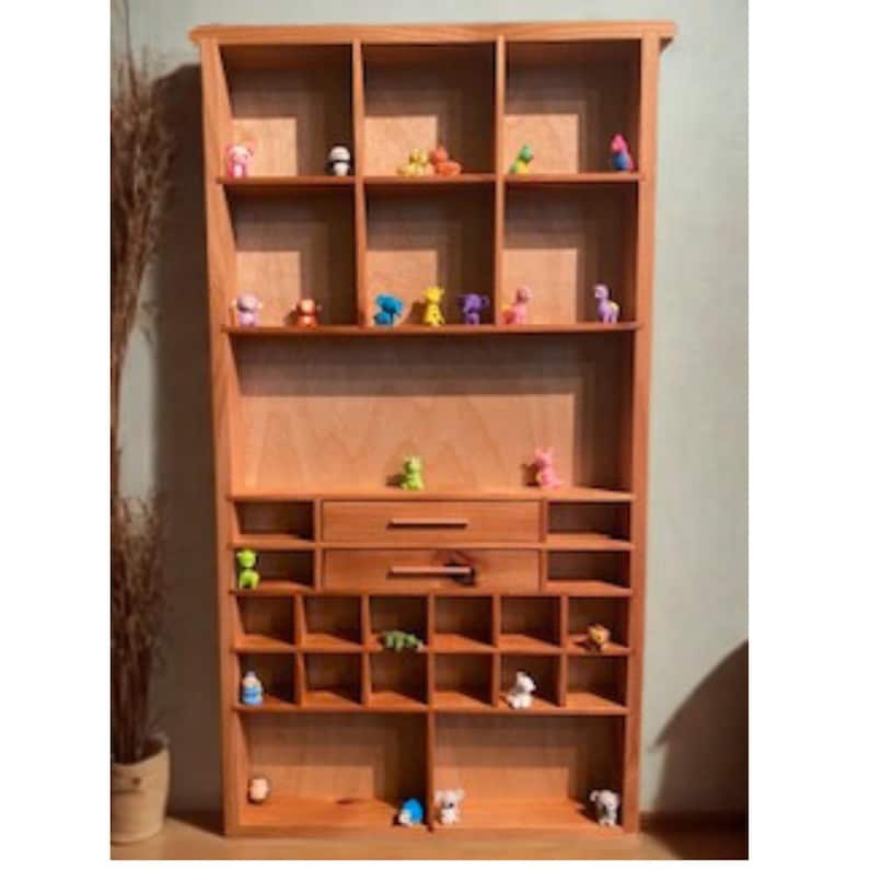 May include: A tall, light-brown wooden shelving unit featuring a variety of rectangular cubby holes of different sizes, two central horizontal drawers with wooden handles, and numerous small, colorful animal figurines placed on the shelves.
