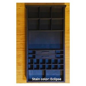 May include: A dark blue wooden organizer shelf featuring a rectangular frame with multiple compartments of varying sizes, including three top cubbies, two central drawers with horizontal handles, and a grid of smaller square storage sections below.