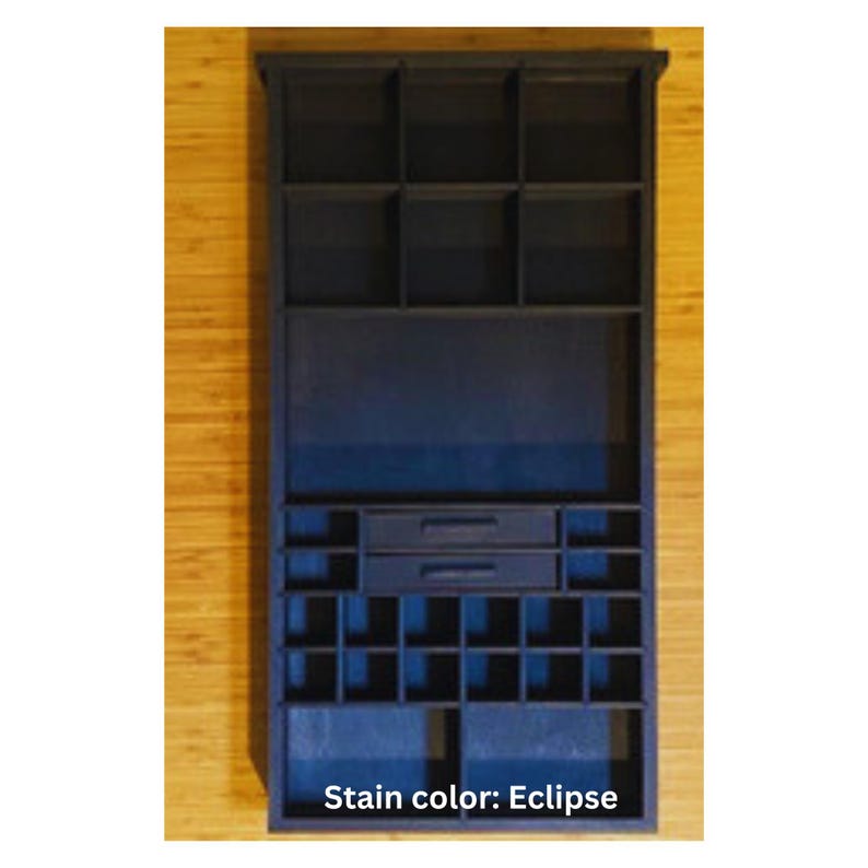 May include: A dark blue wooden organizer shelf featuring a rectangular frame with multiple compartments of varying sizes, including three top cubbies, two central drawers with horizontal handles, and a grid of smaller square storage sections below.