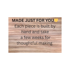 May include: A rectangular sign with a light brown wood grain background featuring black text that reads: MADE JUST FOR YOU, Each piece is built by hand and take a few weeks for thoughtful making, accompanied by a small yellow heart icon.