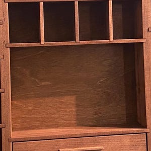 Puede incluir: Un organizador de pared de madera marr&oacute;n que presenta una secci&oacute;n superior con cuatro compartimentos rectangulares abiertos y una secci&oacute;n inferior que contiene dos cajones horizontales, cada uno con un tirador de madera fino.