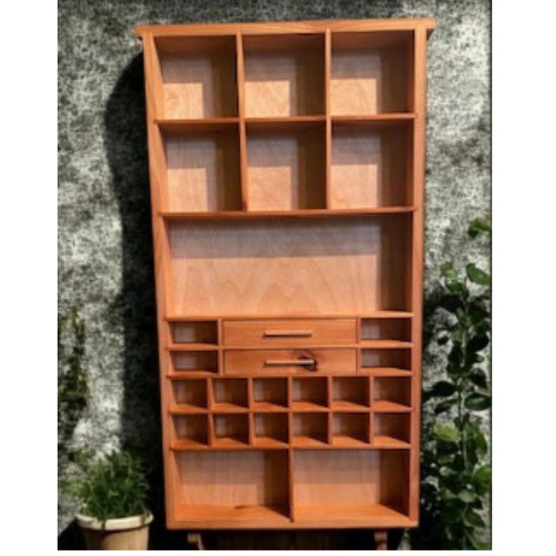 Handcrafted vertical wooden wall display shelf with multiple compartments of varying sizes and two small drawers in the center. The piece has a natural wood finish and is displayed against a rustic wooden backdrop — perfect for showcasing crystals, miniatures, or ceramics.