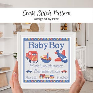 May include: A framed cross stitch pattern featuring the text Baby Boy, Antonio Luis Hernandez, September 22, 2022, 7 lbs. 6 oz., and 21 inches. The design includes a red truck, a blue boat, a blue airplane, a train, and two small cars.