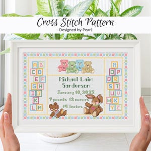 May include: Cross stitch pattern in a white frame. The design includes colorful teddy bears, alphabet blocks, and a name, date, and measurements. The text reads "Michael Laim Sanderson, January 10, 2025, 7 pounds 13 ounces, 19 inches."