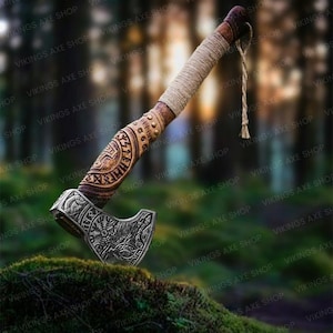 May include: A hand-crafted Viking axe with a wooden handle and a metal head. The handle is decorated with intricate carvings and the head features a detailed design of a wolf's head. The axe is resting on a bed of moss.
