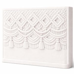 Puede incluir: Panel decorativo rectangular blanco con un diseño en relieve texturizado. El diseño presenta formas de diamante, líneas curvas y elementos en forma de borla, creando un patrón detallado y ornamentado. El panel probablemente está hecho de yeso o un material similar.