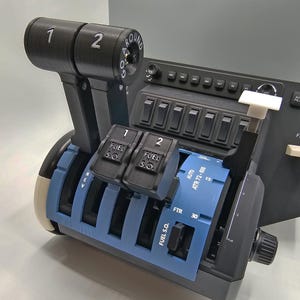 May include: A blue and black aircraft throttle quadrant with a go-around knob, fuel selector switches, and a throttle lever. The quadrant has a blue background with white text and markings. The throttle lever has a black handle with a white number 1 and 2 on it. The go-around knob has a black background with white text that says "GO AROUND".