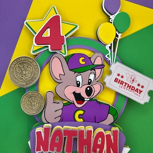 Op de afbeelding: Een kleurrijke taarttopper voor een verjaardag met een cartoonmuis, het nummer 4, ballonnen en de naam "Nathan". Inclusief twee munten met de tekst "Where a kid can be a kid" en het jaar 2008. Een ticket leest "Birthday celebrations".