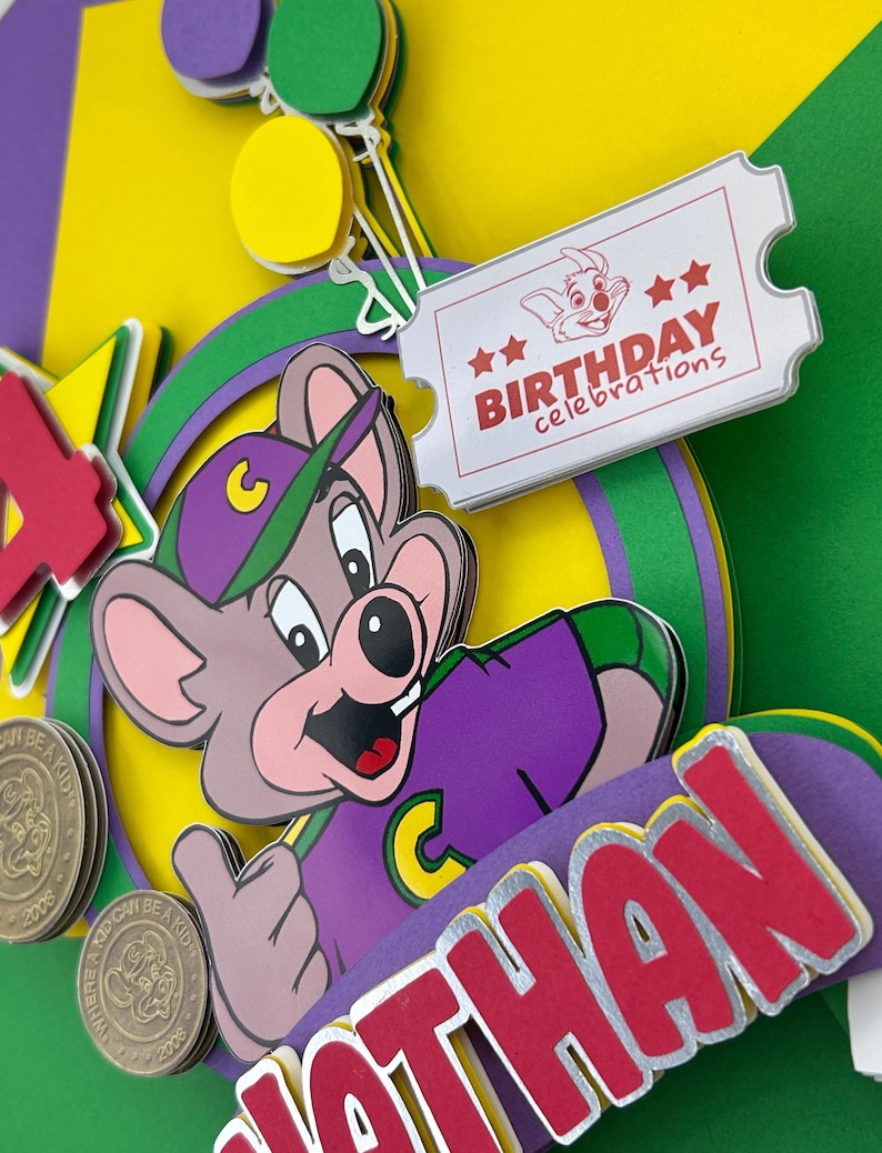 Op de afbeelding: Een kleurrijke verjaardagskaart met een cartoon muis karakter in een paars shirt en groene pet. De kaart bevat de naam "Nathan" in rode letters, een ticket met "Birthday Celebrations" en een rode "4".