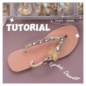 Könnte beinhalten: Ein Tutorial, wie man Sandalen mit Strasssteinen und einem Schmetterlingsanhänger verziert. Die Sandalen sind rosa und haben einen weißen Riemen. Die Strasssteine sind in verschiedenen Farben, darunter rosa, klar und gold. Der Schmetterlingsanhänger ist golden und hat schillernde Flügel.