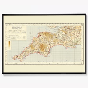 May include: A framed vintage map of the South West Coast Path, with detailed cartography in brown, beige, and red. The map is in a black frame. The title is visible at the top. The map shows the coastline of the South West of England.