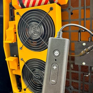 Pu&ograve; includere: Una scatola gialla con due ventole nere e un telecomando nero con un pulsante di accensione, pulsanti pi&ugrave; e meno. La scatola ha un cilindro rosso e bianco a strisce con il testo "K9 Emergency Information" su di esso.