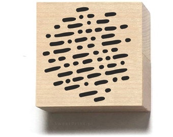 Könnte beinhalten: Ein Stempel aus Holz mit einem schwarz-weißen abstrakten Muster aus Punkten und Strichen. Das Muster hat die Form eines Kreises.