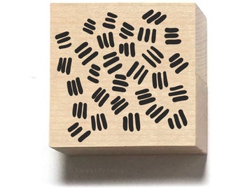Könnte beinhalten: Ein Stempel aus Holz mit einem schwarz-weißen abstrakten Muster aus Linien. Das Muster besteht aus mehreren Linien unterschiedlicher Länge und Dicke.