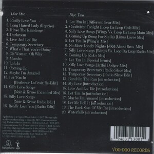 Op de afbeelding: Een cd-hoesje met een zwarte achtergrond en witte tekst met songtitels van twee schijven. De tekst bevat songtitels als "Really Love You", "Let 'Em In" en "Silly Love Songs". De cd is van Voo-Doo Records.