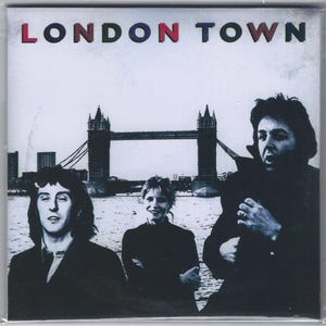 May include: Album cover for "London Town" featuring three people in front of the Tower Bridge. The album title is in red, blue, and white letters. The background is a black and white image of the Tower Bridge and the London skyline.