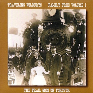 May include: A sepia-toned photo of a group of people standing in front of a train. The train is labeled "282". The people are all dressed in vintage clothing. The photo is titled "Traveling Wilburys Family Tree Volume I The Trail Goes On Forever".