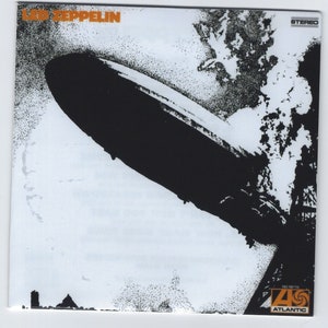 Könnte beinhalten: Ein schwarzes und weißes Albumcover mit dem Text "LED ZEPPELIN" in orangefarbenen Buchstaben. Das Cover zeigt ein schwarzweißes Bild eines Luftschiffs, das über einem bewölkten Himmel fliegt. Das Albumcover enthält auch den Text "STEREO" und das Logo von Atlantic Records.