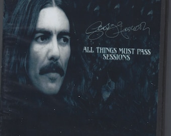 Puede incluir: Una fotografía en blanco y negro de George Harrison sobre un fondo azul oscuro. El texto "MISTERCLAUDEL SPECIAL EDITION FROM HISTORICAL ORIGINAL MASTER RECORDINGS" está en la parte superior de la imagen. El texto "ALL THINGS MUST PASS SESSIONS" está en la parte inferior de la imagen.