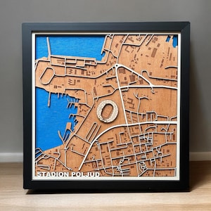 Puede incluir: Un mapa de madera de una ciudad con un estadio en el centro. El mapa está enmarcado en negro y tiene el texto "STADION POLJUD" en la parte inferior.