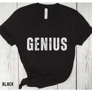 May include: Black t-shirt with the word "GENIUS" printed in white on the front. The text has a distressed, vintage look.
