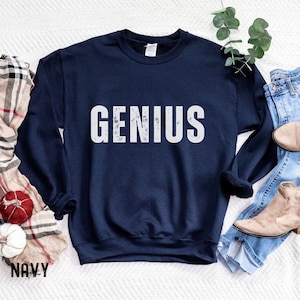 May include: A navy blue sweatshirt with the word "GENIUS" printed in white with a distressed, vintage look.