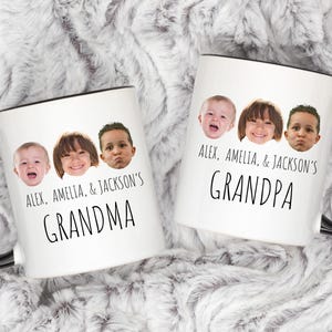 May include: Two white ceramic mugs with black handles and rims. Each mug features a collage of three children's faces above the words "GRANDMA" and "GRANDPA", with the names "Alex, Amelia, & Jackson's" above the words.